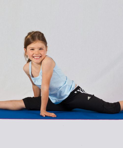 Smiling woman feeling energetic and stretching on a yoga mat.